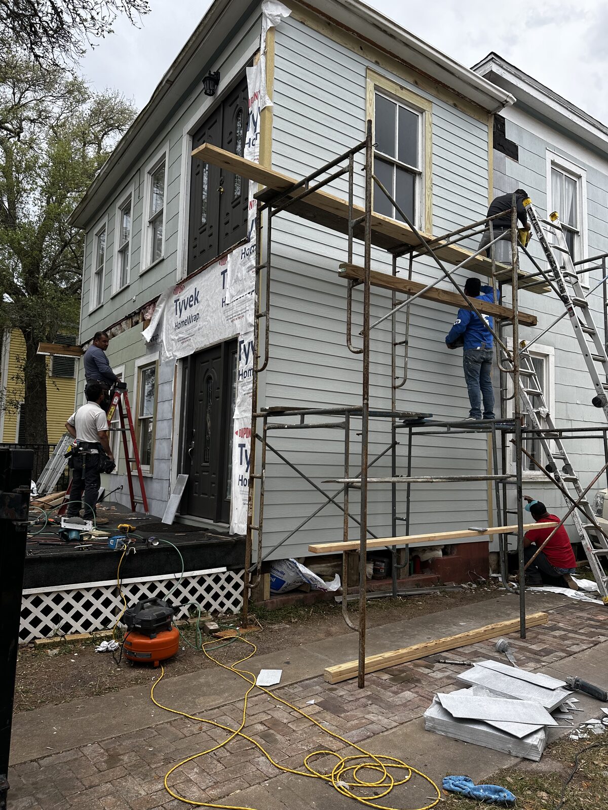 Crew re-siding a historic Galveston home from scaffolding
