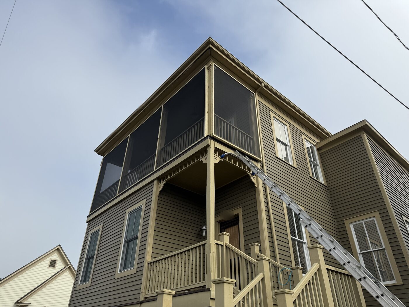Extension ladder set against a two-story building's upper level for an exterior and roofline check during scheduled facility maintenance